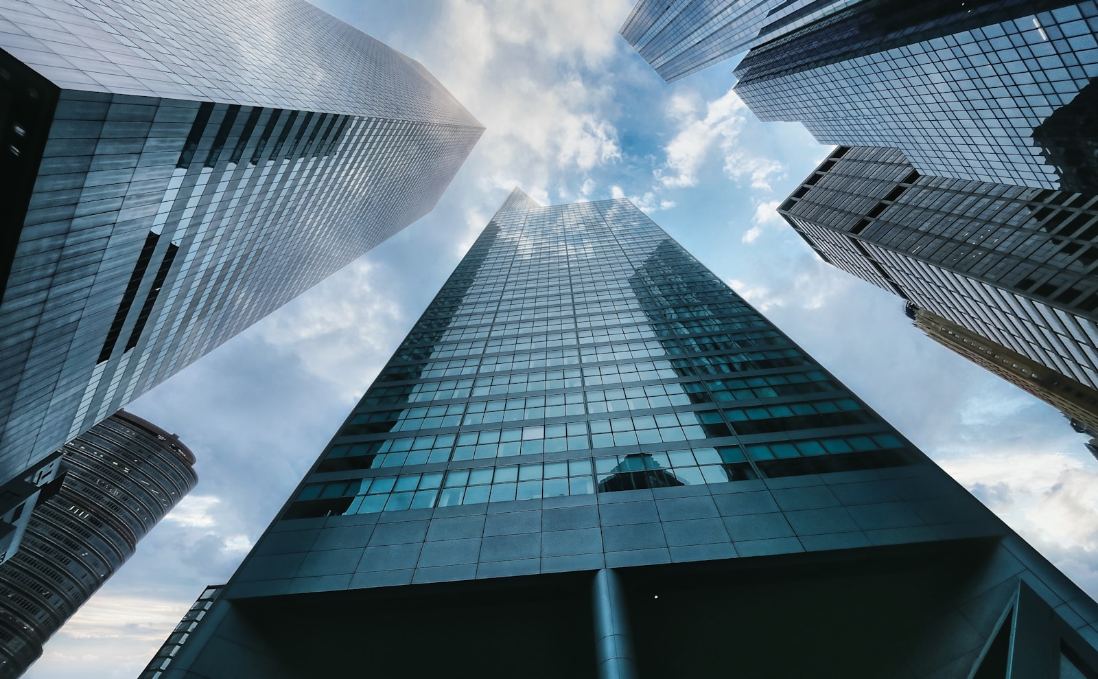 Photo by Clay LeConey low angle photography of high rise building under white clouds during daytime